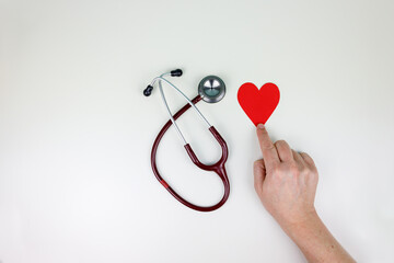 Doctor's hand next to a red heart and stethoscope, concept of health and prevention