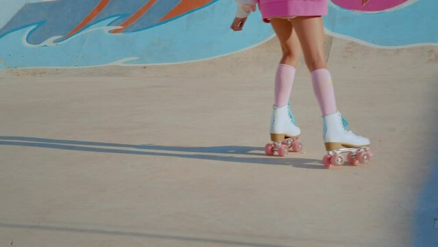 Cropped view of the child girl wearing vivid clothes training riding at roller skates at open air rollerdrome. Happy childhood concept