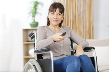 woman in wheelchair changing tv channel