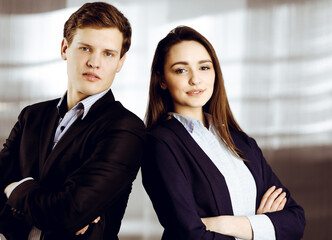 Friendly young colleagues are standing as a team with crossed arms in a modern office. Portrait of successful business people at work.