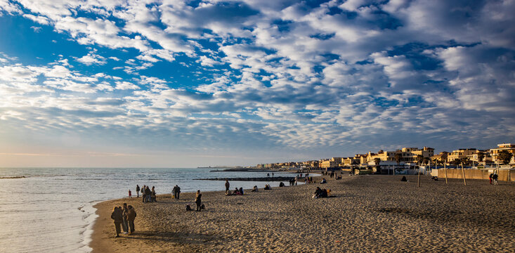 February 12, 2023 - Ostia, Rome, Italy. The sea of Ostia, on the Roman coast, on a winter Sunday. People enjoy the public holiday by walking on the beach in the open air in the evening.