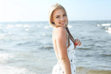 Fototapeta na wymiar Happy blonde woman in free happiness bliss on ocean beach standing straight and posing.
