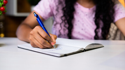 close up shot of girl hands writing or making notes on study desk at home.