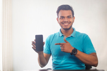 Portrait of a young man showing mobile phone in his hand