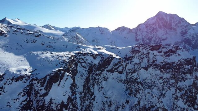 Aerial drone video of sideways flight over scenic snowy mountain range and rocky ridge in winter in the European Alps