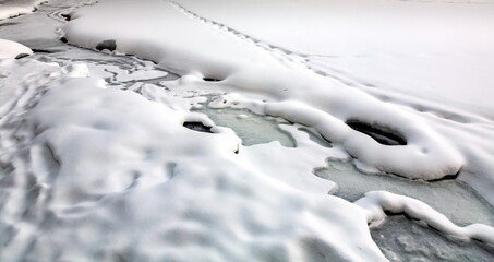 Open water of a snow-covered frozen river in winter close-up