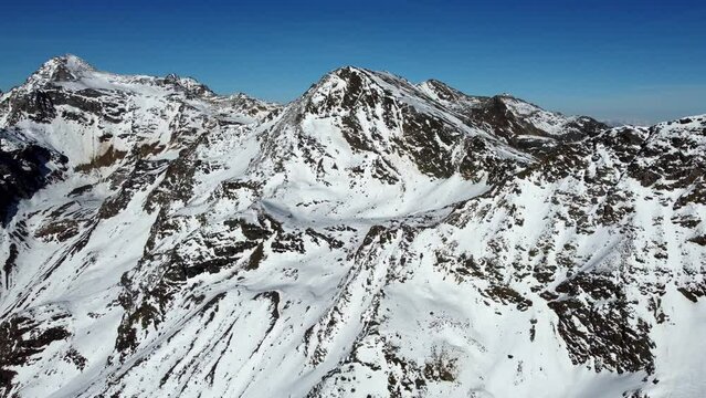 Aerial drone video of sideways flight over snowy mountain range in winter in the European Alps