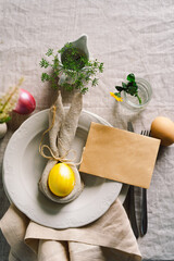 Happy Easter. Stylish easter eggs on a napkin with spring flowers on white wooden background. Table setting. The concept of a happy Easter holiday.