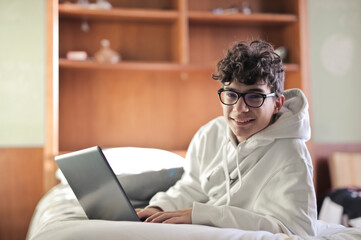 young boy on the bed with his computer - 577417870