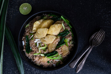 Pineapple fried rice has minced pork and vegetable in plate on stone table.