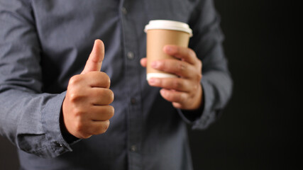 Businessman show thumb and holding favorite hot coffee cup. Excellent review drink business concept