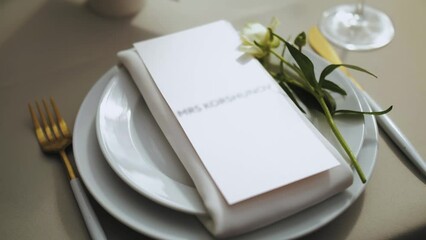 Beautiful wedding decor, all decorated in white, green colors style. Classic served plates with tender flower and golden fork on the table. camera moving slow motion. 