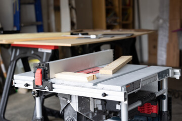 Wooden plank cut in half placed on top of table saw in woodworker shop