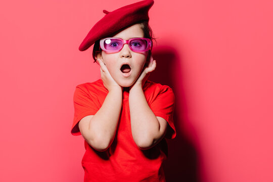 Shocked kid in red shirt and beret looking at camera