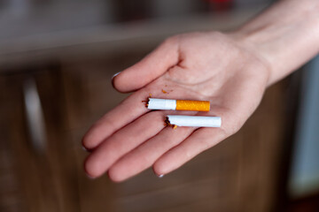 Break a cigarette. A woman holds a broken cigarette in her hands. Happy woman shows a broken cigarette in her palm. Quit bad habit, healthcare concept. Quit smoking