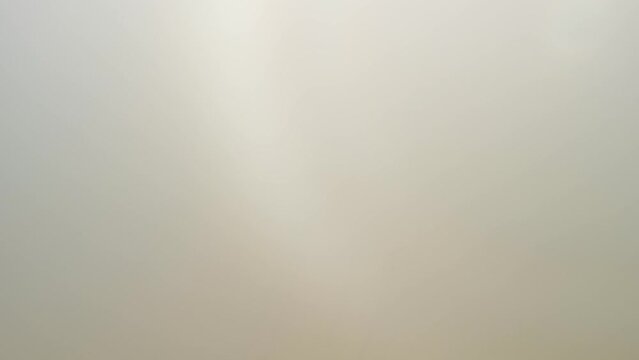Coming out dense fog over golden wheat field to see the sky above. Aerial shot.