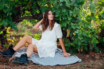 a woman in a white dress and black boots in a vineyard