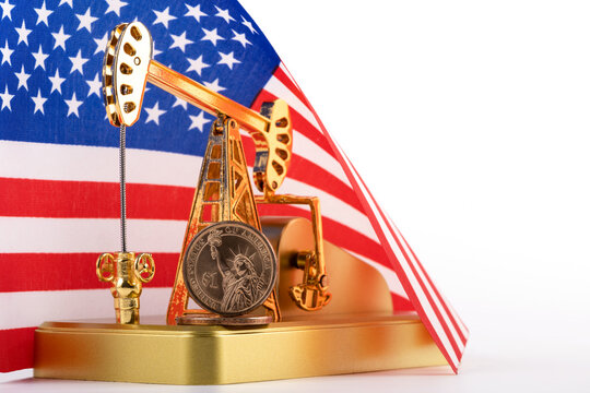 Gold oil pump and one dollar coin against the background of the Stars and Stripes American flag