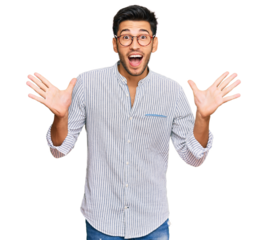 Young handsome man wearing casual clothes and glasses celebrating crazy and amazed for success with arms raised and open eyes screaming excited. winner concept