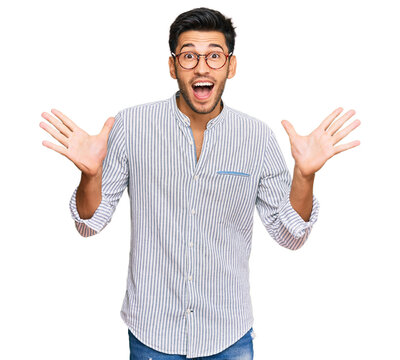 Young handsome man wearing casual clothes and glasses celebrating crazy and amazed for success with arms raised and open eyes screaming excited. winner concept