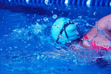 Successful female swimmer swimming in the pool. A professional athlete is determined to win the championship.