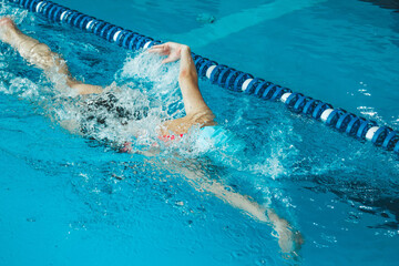 Beautiful female swimmer using front bypass, freestyle in the pool. Preparing professional athletes...
