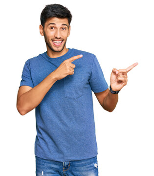 Young handsome man wearing casual clothes smiling and looking at the camera pointing with two hands and fingers to the side.