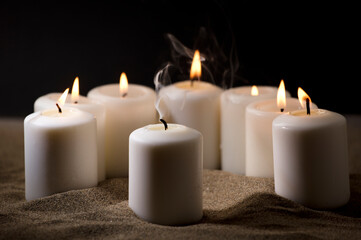 Fototapeta na wymiar bullying concept, composed by group of lit candles, on sand with black night background