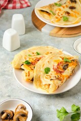 Hearty wheat pancakes with ham, mushrooms and cheddar cheese on a white plate on a gray concrete background. International Pancake Day, Maslenitsa.