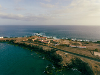 Fototapeta premium Aerial photos of Farol da Praia in Santiago, Cape Verde showcase a stunning lighthouse on a rugged coastline with breathtaking views of the Atlantic Ocean, surrounded by dramatic cliffs, sandy beaches