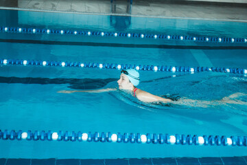 Beautiful female swimmer using front bypass, freestyle in the pool. Preparing professional athletes...