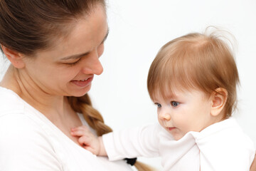 Bright portrait of happy mother holding infant child on hands. Mother hugging her little 6 months old baby.
