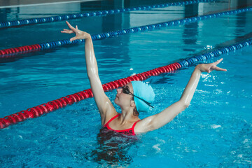 Synchronized girl working out tricks in the pool. Synchronized swimming, sports in the water....