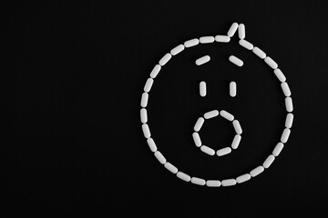 Cara de pastillas blancas sorprendida sobre fondo negro, espacio para texto al lado izquierdo. 