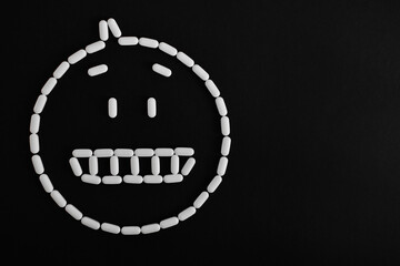 Fototapeta na wymiar Emoji de cara de pastillas blancas, sobre fondo negro.