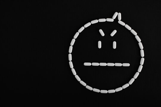 Cara de pastillas blancas enojada, sobre fondo negro. Espacio para texto al lado izquierdo.