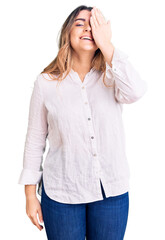 Young caucasian woman wearing casual clothes covering one eye with hand, confident smile on face and surprise emotion.