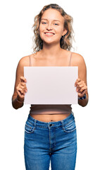 Beautiful caucasian woman holding blank empty banner looking positive and happy standing and smiling with a confident smile showing teeth