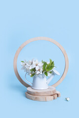 Spring still life composition with miniature watering can and cherry blossoms on woodcut