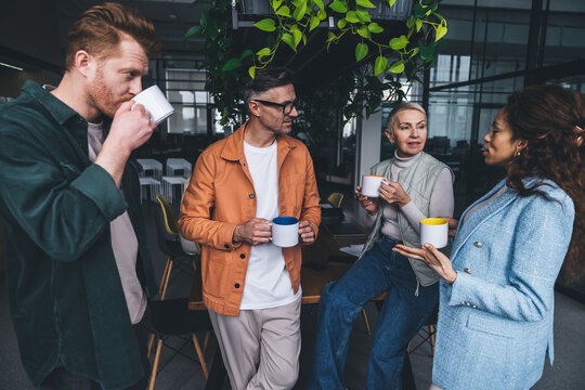 Positive colleagues having drinks and communicating during break