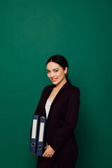 a business woman in a black suit stands with folders in an office space