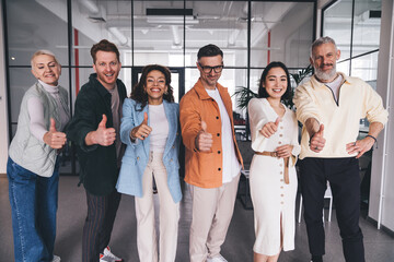 Group of diverse professionals standing in office showing like gesture