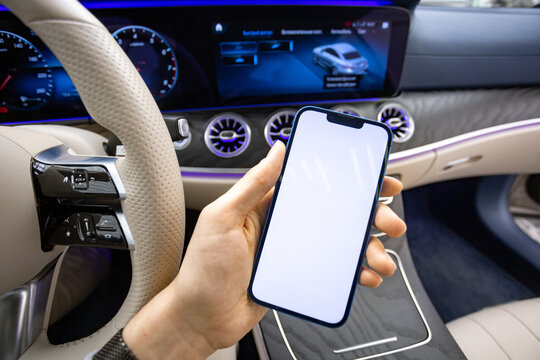 The hand of a man with a iphone 13 blue a Mercedes E-Class
