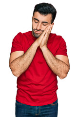 Hispanic man with beard wearing casual red t shirt sleeping tired dreaming and posing with hands together while smiling with closed eyes.
