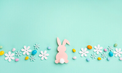 Pink Bunny, Easter Eggs with Sweets and Spring Flowers on Blue Mint Background