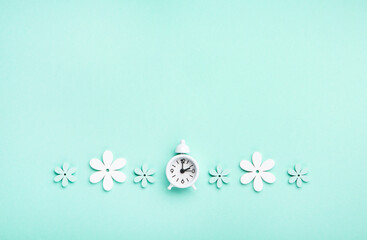 White Alarm Clock and Spring Daisy Flowers on Blue Background