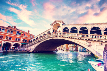 Fototapeta na wymiar Bright charming landscape with Rialto Bridge at sunset in Venice, Italy. Amazing places. Popular tourist atraction.