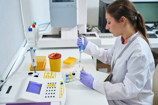 Female laboratory assistant uses special pipette to work with biomaterial