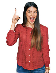 Young hispanic woman wearing casual clothes pointing finger up with successful idea. exited and happy. number one.