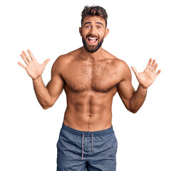 Fototapeta premium Young hispanic man wearing swimwear shirtless celebrating crazy and amazed for success with arms raised and open eyes screaming excited. winner concept